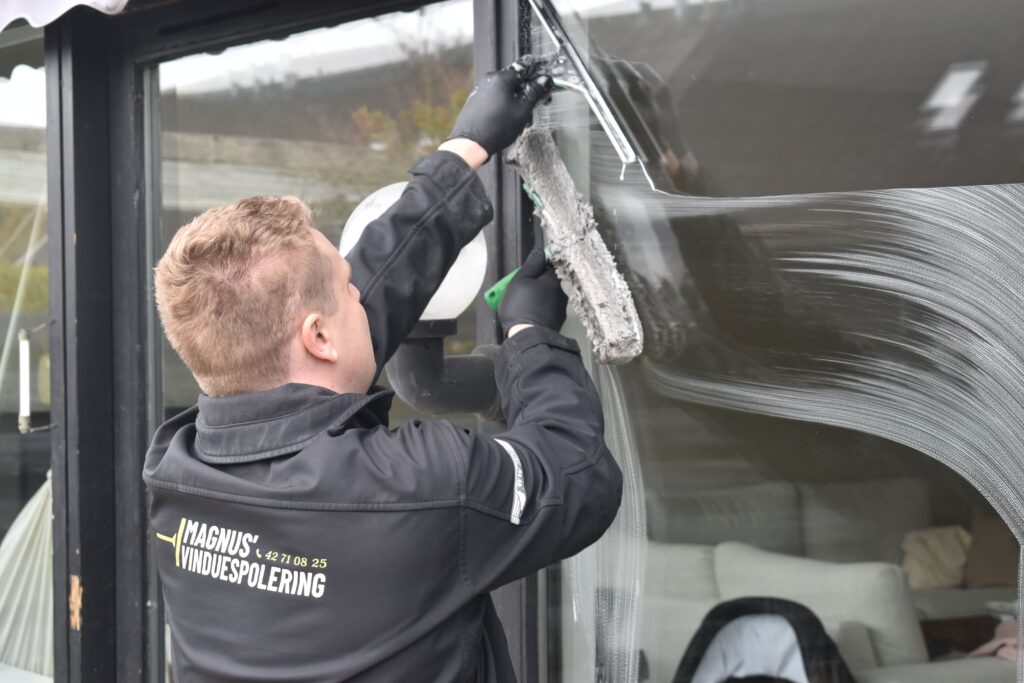 Professional cleaning service washing a large glass window. Clean and efficient work by a dedicated individual.